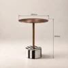 Discover the Clara Side Table at Majestic Home UAE. A bronze-toned round top and black-and-white striped base bring sculptural style to your living room.